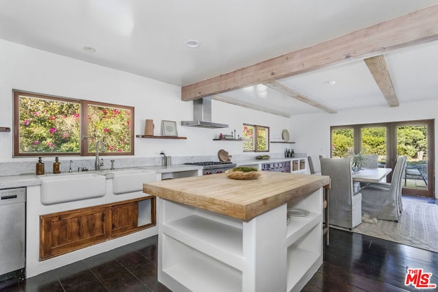 kitchen featuring wall chimney range hood, sink, dark hardwood / wood-style floors, appliances with stainless steel finishes, and butcher block counters