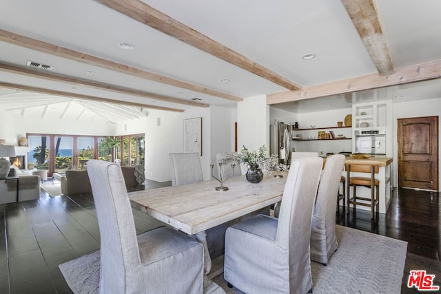 dining space with dark hardwood / wood-style floors and lofted ceiling with beams