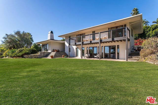 rear view of house featuring a yard, a balcony, and a patio area