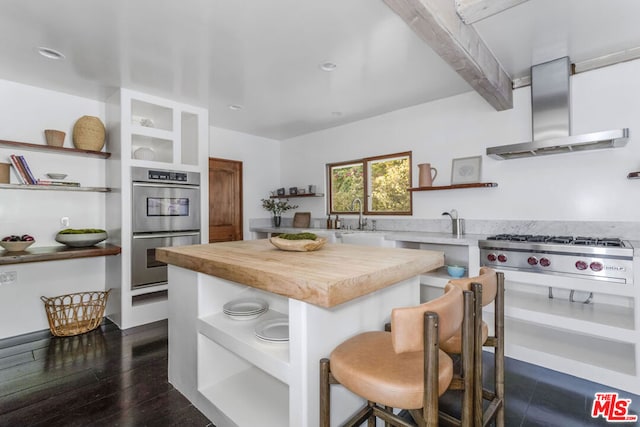 kitchen with sink, dark wood-type flooring, extractor fan, a kitchen bar, and appliances with stainless steel finishes