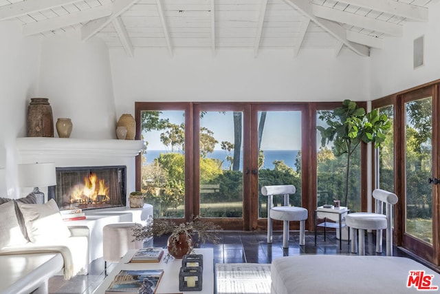 sunroom / solarium with vaulted ceiling with beams, a wealth of natural light, a fireplace, and french doors