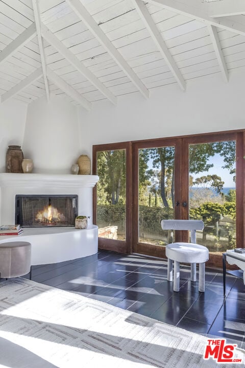 tiled living room featuring a large fireplace, beamed ceiling, french doors, and high vaulted ceiling