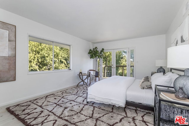 bedroom featuring multiple windows, hardwood / wood-style floors, and french doors