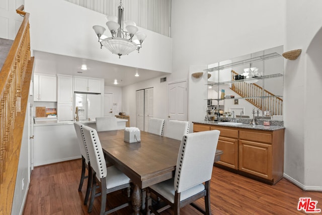 dining area featuring hardwood / wood-style floors, an inviting chandelier, and a high ceiling