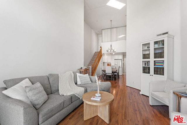 living room featuring dark hardwood / wood-style floors, a towering ceiling, and a chandelier