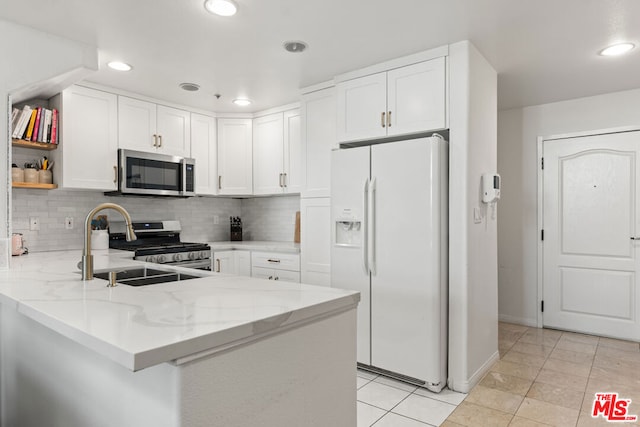 kitchen featuring white cabinetry, kitchen peninsula, appliances with stainless steel finishes, and tasteful backsplash