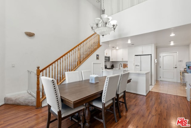 dining room with hardwood / wood-style floors, a high ceiling, and an inviting chandelier