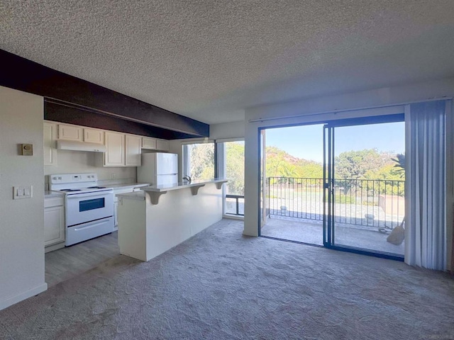 kitchen with a kitchen breakfast bar, a textured ceiling, white appliances, light carpet, and white cabinets