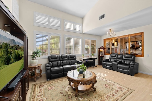 living room featuring plenty of natural light, light hardwood / wood-style floors, high vaulted ceiling, and a chandelier