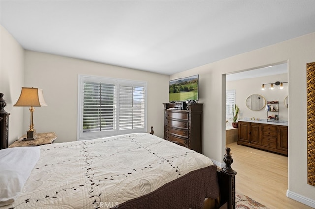 bedroom featuring light hardwood / wood-style floors and ensuite bath