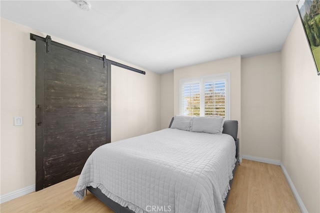 bedroom with a barn door and light hardwood / wood-style flooring