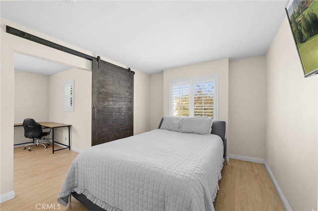 bedroom featuring a barn door and light wood-type flooring