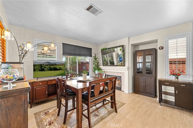 dining area featuring a healthy amount of sunlight, light hardwood / wood-style floors, and a tile fireplace