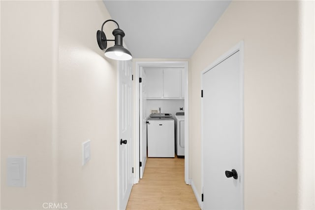 hallway with washer and dryer and light wood-type flooring