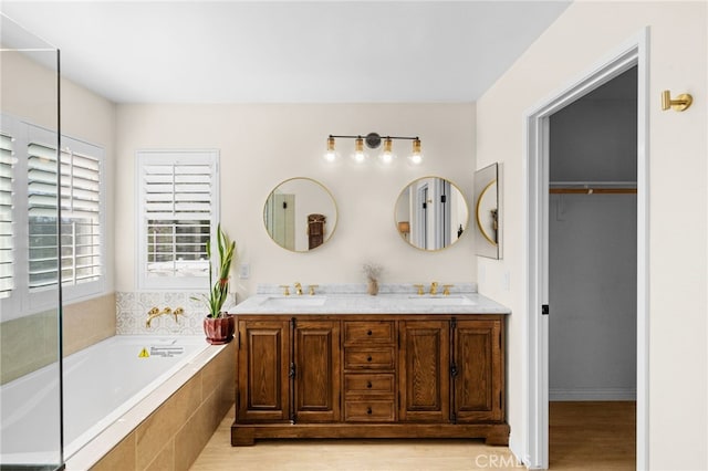 bathroom with vanity, a relaxing tiled tub, and hardwood / wood-style flooring