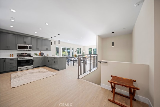 kitchen with gray cabinets, kitchen peninsula, decorative light fixtures, and appliances with stainless steel finishes