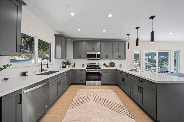 kitchen featuring gray cabinetry, decorative light fixtures, plenty of natural light, and stainless steel appliances