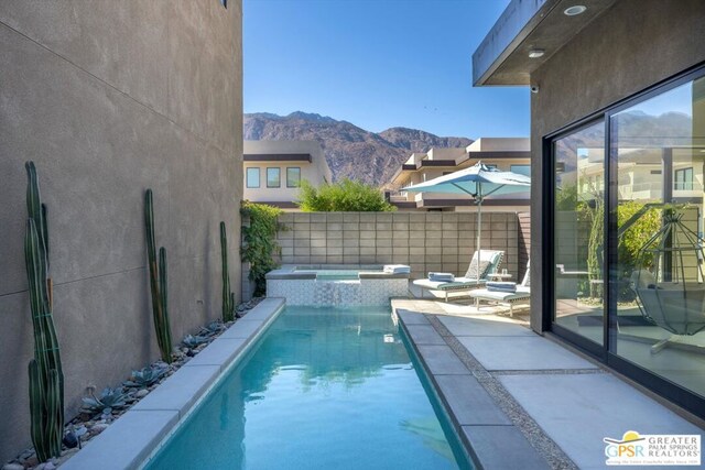 view of pool featuring an in ground hot tub, a mountain view, and a patio