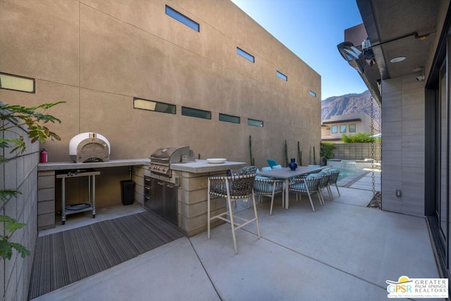 view of patio with a mountain view, a grill, and exterior kitchen