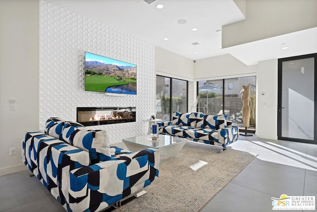 living room featuring a multi sided fireplace and concrete flooring