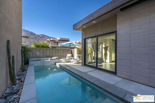 view of swimming pool with a patio area, an in ground hot tub, and a mountain view