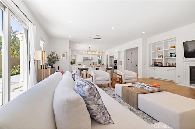 living room with an inviting chandelier, light hardwood / wood-style flooring, and built in features