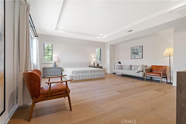 bedroom with a raised ceiling and light wood-type flooring