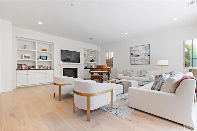 66 Poncho, Irvine, CA 92602 - living room featuring light wood-style flooring, a glass covered fireplace, built in features, and recessed lighting