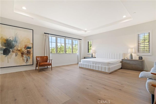 bedroom featuring a raised ceiling and light wood-type flooring