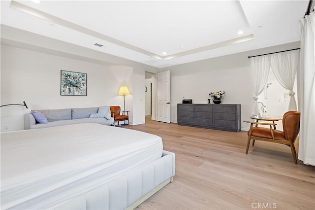 bedroom with a tray ceiling and light hardwood / wood-style flooring