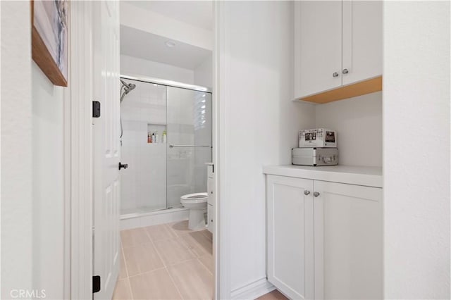 bathroom featuring vanity, toilet, tile patterned flooring, and a shower with door