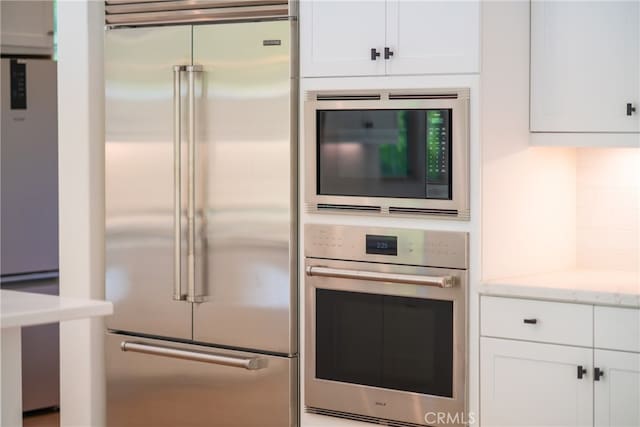 66 Poncho, Irvine, CA 92602 - kitchen with built in appliances, white cabinets, and light stone countertops