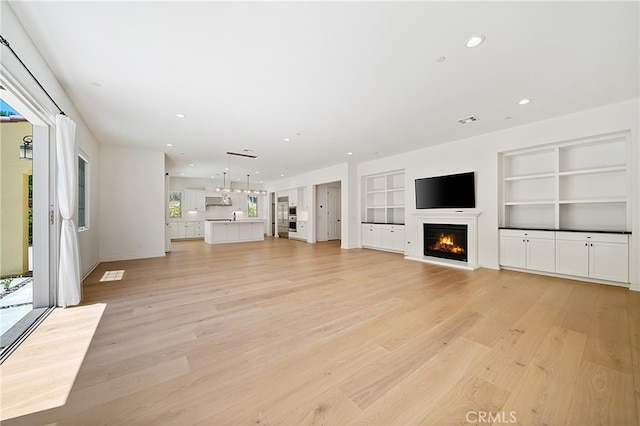 66 Poncho, Irvine, CA 92602 - unfurnished living room with a glass covered fireplace, light wood finished floors, built in features, and recessed lighting