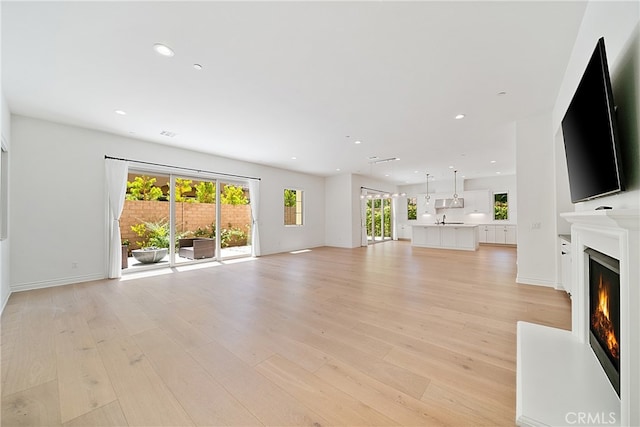 66 Poncho, Irvine, CA 92602 - unfurnished living room featuring a lit fireplace, light wood-style flooring, and recessed lighting
