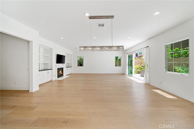 66 Poncho, Irvine, CA 92602 - unfurnished living room featuring built in features, recessed lighting, light wood-type flooring, and a lit fireplace