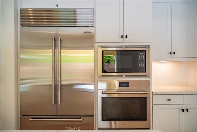 66 Poncho, Irvine, CA 92602 - kitchen with built in appliances, white cabinets, tasteful backsplash, and light stone countertops
