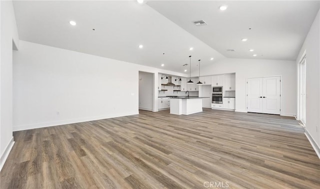 unfurnished living room with lofted ceiling, recessed lighting, visible vents, baseboards, and light wood-type flooring