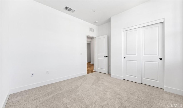 unfurnished bedroom with light carpet, baseboards, visible vents, and a closet