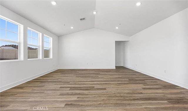 spare room featuring lofted ceiling, dark wood finished floors, visible vents, and recessed lighting