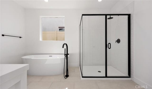 full bath featuring a stall shower, a soaking tub, baseboards, and tile patterned floors