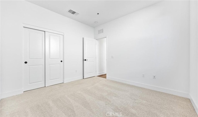 unfurnished bedroom featuring a closet, visible vents, light carpet, and baseboards