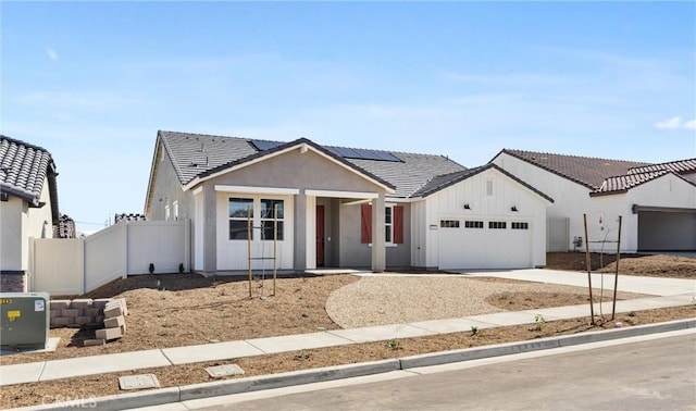 view of front of property featuring a tile roof, concrete driveway, roof mounted solar panels, fence, and a garage