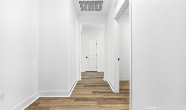 corridor with wood finished floors, visible vents, and baseboards