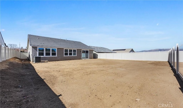 rear view of house with cooling unit, a fenced backyard, and stucco siding