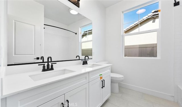 full bath featuring baseboards, a sink, toilet, and double vanity