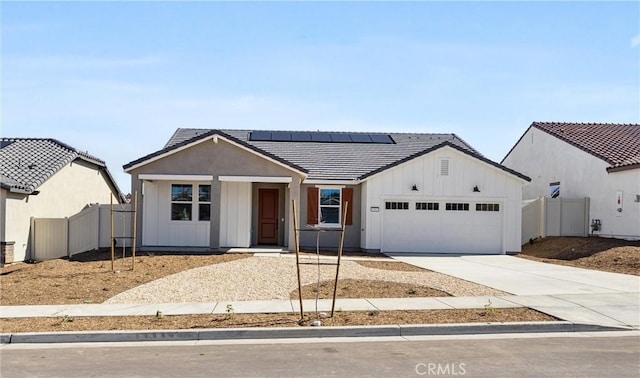 view of front of property with an attached garage, concrete driveway, a tiled roof, roof mounted solar panels, and board and batten siding