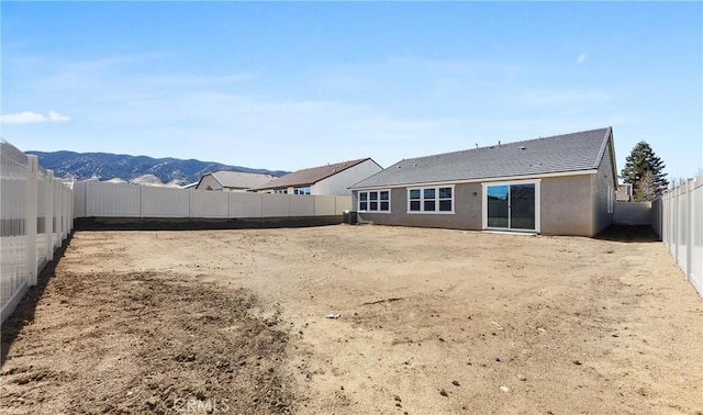 rear view of property featuring a fenced backyard, a mountain view, and stucco siding