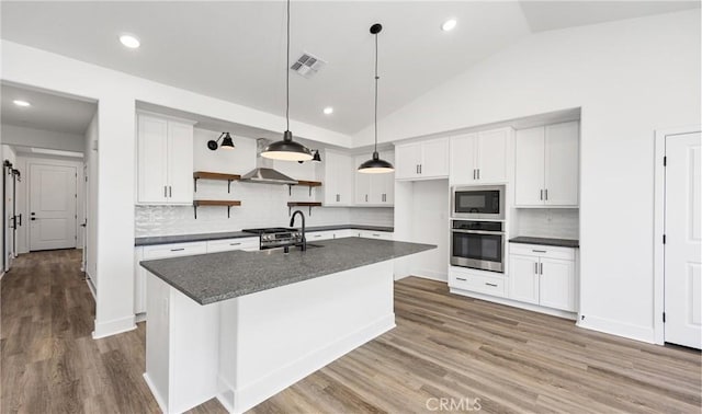 kitchen with a kitchen island with sink, a sink, white cabinetry, stainless steel oven, and built in microwave