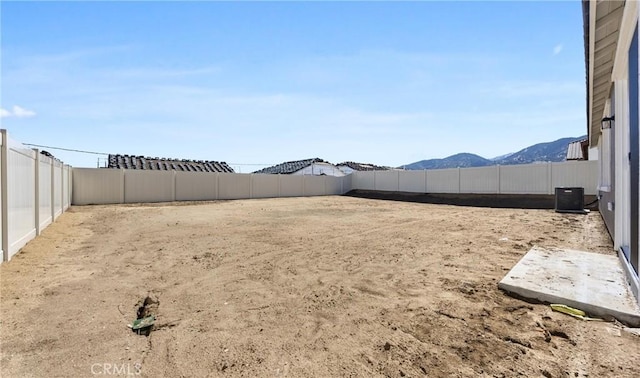 view of yard featuring a fenced backyard, a mountain view, and central air condition unit