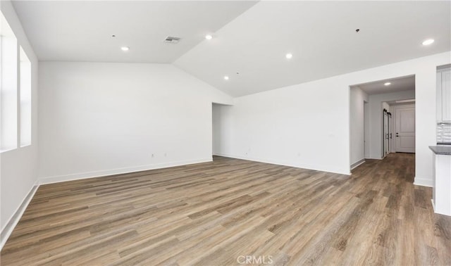 empty room with lofted ceiling, visible vents, wood finished floors, and recessed lighting